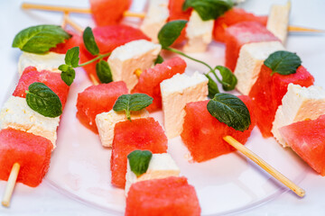 watermelon canapes with cheese sprinkled with mint on a plate