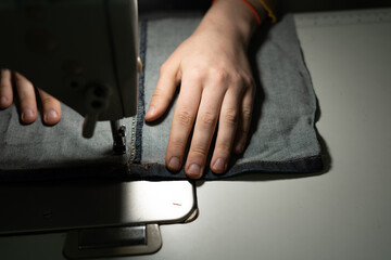 Hands of a young girl in a sewing workshop. Sewing on a zipper on a sewing machine. Sewing concept.