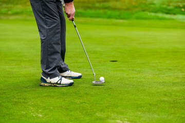 Close-up of a golf player who with a putt pocket the ball on the green