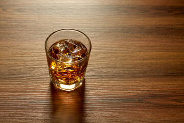 A Glass of whiskey on ice on wood table