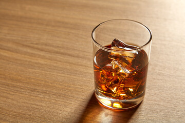 A Glass of whiskey on ice on wood table