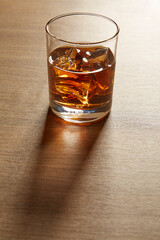 A Glass of whiskey on ice on wood table