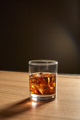 A Glass of whiskey on ice on wood table