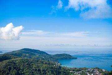 The landscape of the mountain ridge of Phuket and the Adaman Sea against the background of a blue sky with clouds.