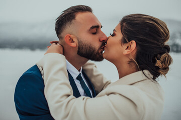 Bride and groom among snowy mountain. They are standing and hugging. Winter wedding outdoors. Close up.