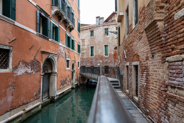 Fototapeta na wymiar ein enger Kanal in San Marco, Venedig, mit alten Häusern und einer eisernen Brücke entlang und über den Kanal