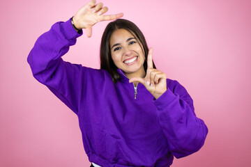 Young beautiful woman wearing sweatshirt over isolated pink background smiling making frame with hands and fingers with happy face