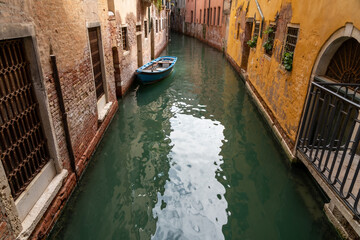 ein schmaler Kanal in San Polo, Venedig mit einem blauen Boot in grünem Wasser