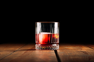 Side view on negroni cocktail in old fashioned glass on the wooden table