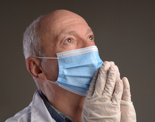  Senior medical doctor in protective gloves and face mask over grey background