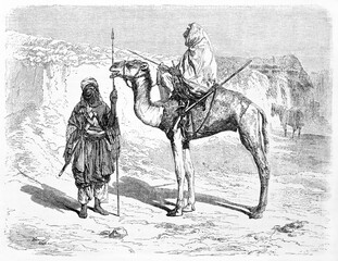 Two Tuareg men outdoor in the warm desert in their typical costumes. One on camel back. Sahara, Algeria. Ancient grey tone etching style art by Hadamard, Le Tour du Monde, 1861 - 403779340
