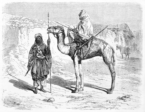 Two Tuareg men outdoor in the warm desert in their typical costumes. One on camel back. Sahara, Algeria. Ancient grey tone etching style art by Hadamard, Le Tour du Monde, 1861