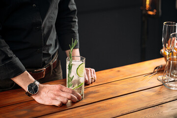 Closeup on man holding fresh gin tonic cocktail with lime slices