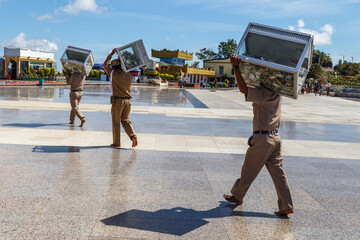Myanmar (Burma). Collectors on the square near Kyaiktiyo Pagoda carry transparent boxes filled with...