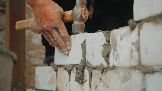 Construction worker or mason laying bricks and creating walls. Bricklayer laying bricks to make a wall. Building a cement block wall for a house.