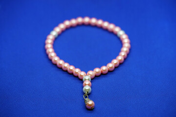 Selective focus of silver and pink beaded tasbih or tasbeeh isolated on blue background