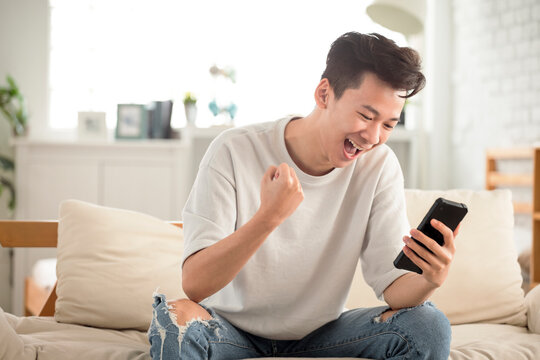happy young man  looking at cell phone celebrate receiving  good news