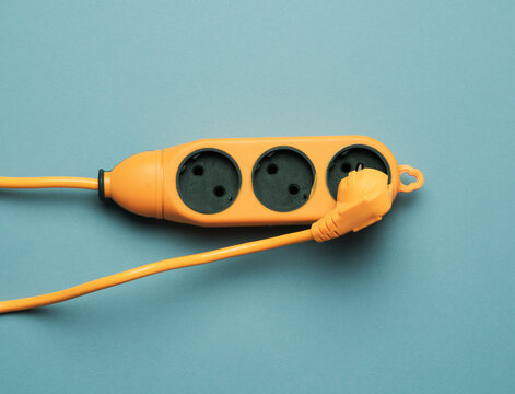 Rubber Orange Power Strip With Three Sockets On A Blue Background