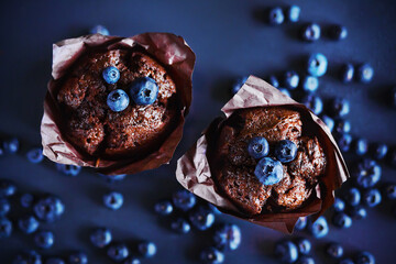 Top view of delicious chocolate cupcakes with blueberry filling, around which lie ripe berries of...