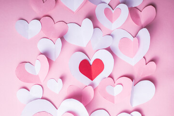 Valentine's Day festive background with pink and white paper hearts on a pink background for Valentines  holiday. Flatlay. Top view. Copyspace.