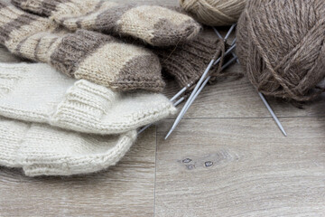Skeins of thread and knitted mittens on a wooden background. The concept of hobby, home production and individual entrepreneurship.