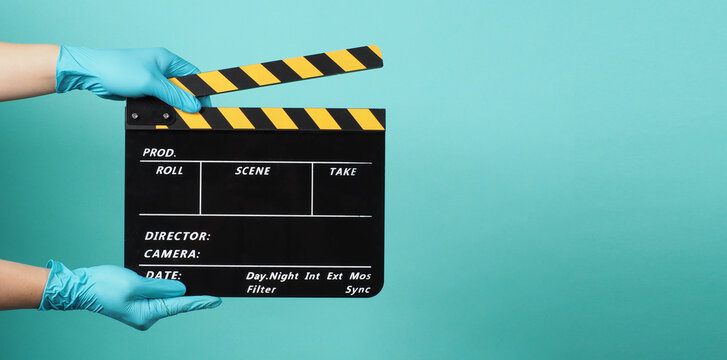 Hand wear madical gloves or blue latex glove gloves and hold black Clapper board or movie slate . it use in movies production and cinema industry on blue and green,mint background