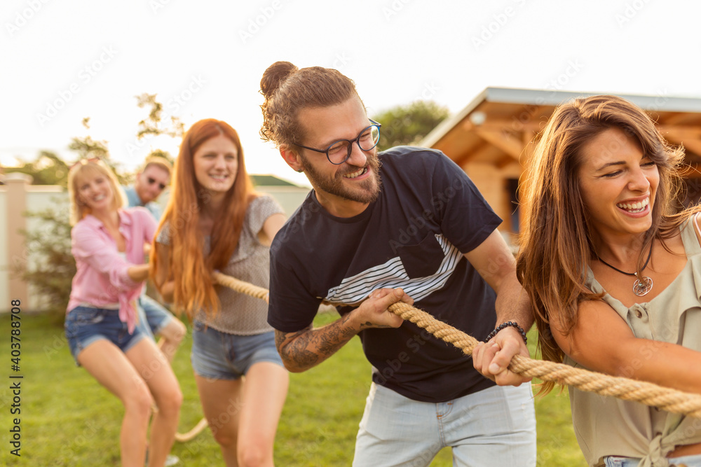 Wall mural Friends playing tug of war at an outdoor summertime party