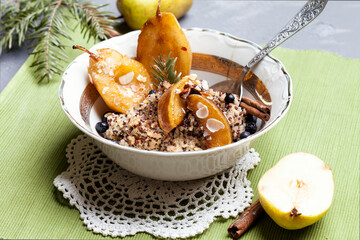 Vegan quinoa porridge with caramel, blueberries, sliced ​​pear, honey on a ladle in a bowl with ingredients above and a cloth napkin on a gray texture background. View from above. Healthy eating