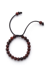 Detailed shot of dark brown bracelet made of wood beads with braided strings. The stylish bracelet is isolated on the white background. 