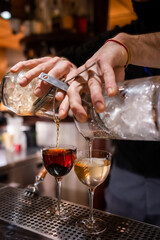 stir and strain cocktails. bartender pouring two stirred cocktails from barglass through strainer.  bartender pouring cocktails in each hand at the same time