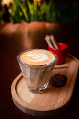 flat white coffee served on wooden coffee tray. glass of cappuccino served on wooden coffee tray with chocolate truffle.  