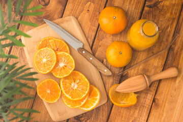 sliced oranges on a chopping board on a wooden table in the kitchen. Squeezing juice from oranges