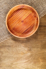 Fototapeta na wymiar Round plate made of natural wood on an old wooden table, top view. Rustic, retro style
