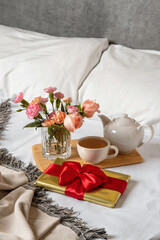 A gift box lies in bed early in the morning. Content for honeymooners and lovers for Valentine's Day.