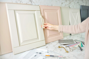 Home improvement concept. Girl the designer chooses the facades and handles for cabinet furniture...