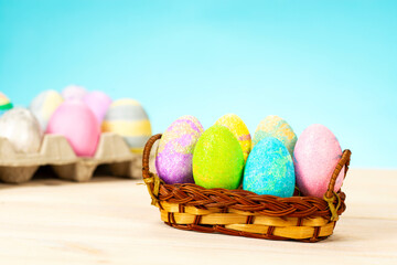 Colorful easter eggs in basket on table on blue background