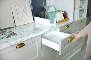 Home improvement concept. young girl designer opens a drawer of a kitchen cabinet in a shop salon.