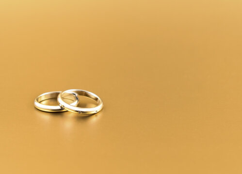 Two wedding rings isolated on a golden background stock images. Engagement rings isolated on a gold background with copy space for text. Wedding rings frame