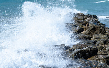 Fototapeta na wymiar Close-up of sea waves breaking on the rocks of Vilanova y la Geltru beach