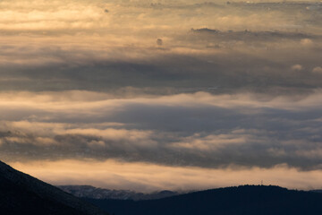 Winter in the Mountains. Beautiful orange mist or fog at sunrise time. Good sunlight and patterns in the landscape. Sea of clouds.
