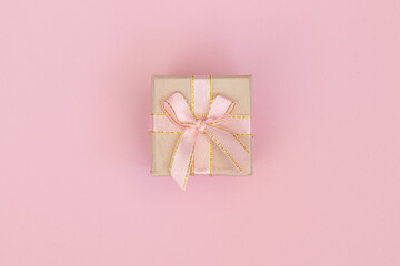 Gift box with pink ribbon bow isolated on pink background. Birthday, wedding or christmas concept. Flat lay