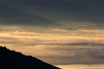 Winter in the Mountains. Beautiful orange mist or fog at sunrise time. Good sunlight and patterns in the landscape. Sea of clouds.