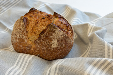 Freshly baked homemade bread with linen cloth, front horizontal view.