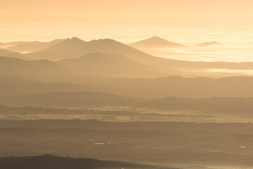 Winter in the Mountains. Beautiful orange mist or fog at sunrise time. Good sunlight and patterns in the landscape. Sea of clouds.