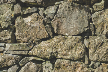 Old stone rock wall surface texture with grass. Close up detail. Pattern abstract background.