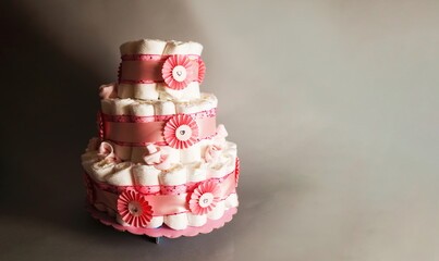 Nappy Cake made from nappies, ribbons and flowers - Baby shower - Pretty pink flower on nappy cake - Gender revealing party present surprise - Gifts and Decorations for a baby nappy cake tort.