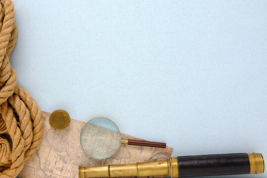 Top view of vintage spyglass, magnifier, map and nautical rope.
