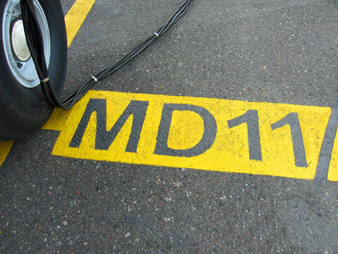 Bug Fahrwerk eines McDonnell Douglas MD11 Flugzeugs am Flughafen an seiner Parkposition markiert mit einem gelben Zeichen auf Asphalt Boden