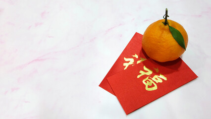 A mandarin orange with red ang pow (a monetary gift given during special occasions in Chinese...