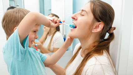 Little toddler boy brushing and cleaning teeth to his mother in bathroom
